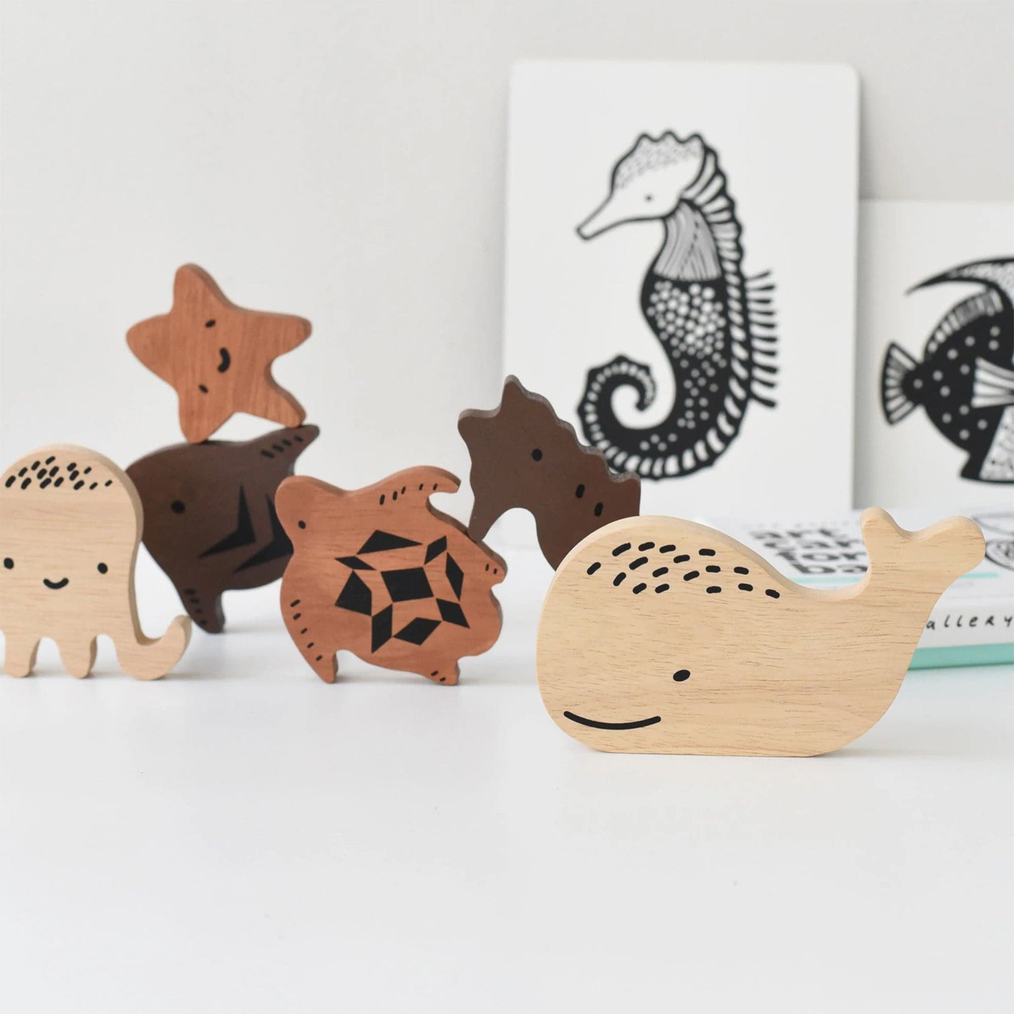 Sweet sea creatures scattered around their puzzle board. There is a starfish, octopus, sea horse, turtle, fish, and whale. Each puzzle piece is wooden and a different color wood.