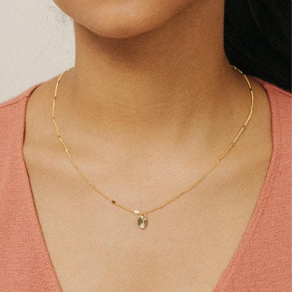 A dainty gold chain with a small circle pendant.