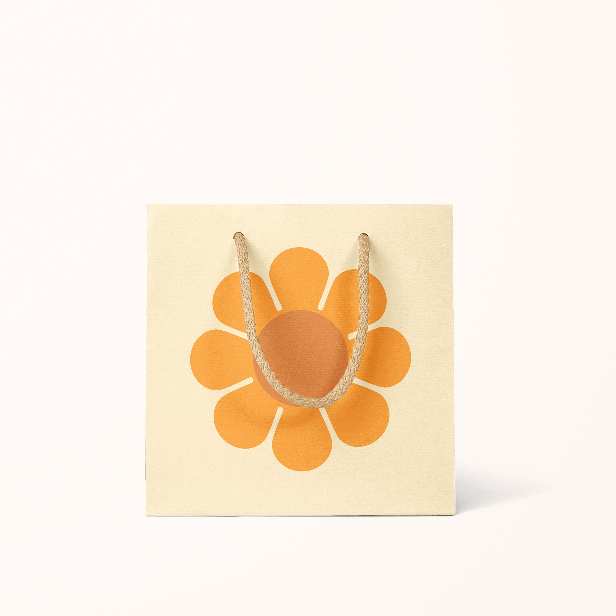 A light yellow gift bag with an orange daisy in the center along with light tan cotton strings.